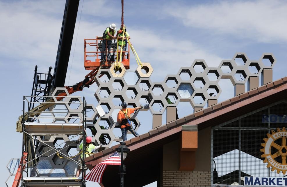 Crews install an art piece on the side and roof of the Rotary Marketplace pavilion Crews install an art piece on the side and roof of the Rotary Marketplace pavilion