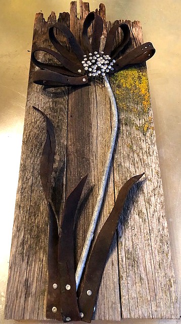 Vintage horse leather with galvenized metal roofing nails mounted on barn wood.