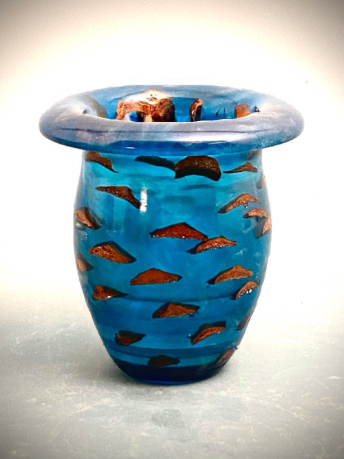 “Pine Cone Bowl”
At a dainty 4X4”, this one likes to sit on a shelf, on a desk, a settee wa, a counter.
I put just enough blue pigment in the dye to make it translucent and just enough gold mica to add a swirl. Then, the pine cone goes in and gets taped to the rim so it won’t ‘float’ too high. The 2-carbonOxygen Aliphatic then sits until its temp rises to ~110*F before I start the fan to keep it cool. If the temp rises to 125*, it takes a quick trip to the freezer to prevent the dreaded’flash cure’ which destroys the magic of cross-linking and polymerization that makes liquid resin into a rock solid blob. 24 hrs later, if it’s hard and has no cracks, it is threaded onto the lathe for carving. A bit of sanding, polishing, and lacquer later and, voila, here it is.