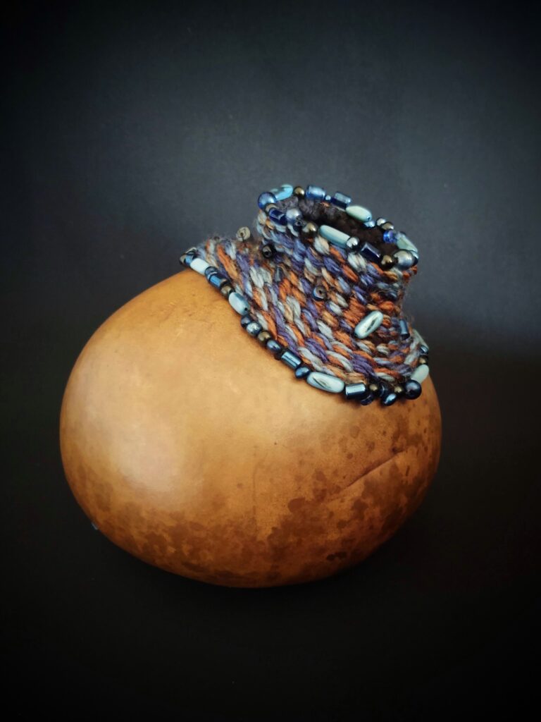 "Canyon Weave" - The gourd is decorated with oil paint, weaving, and beading.