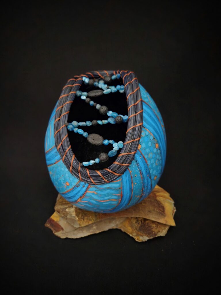 It-Opened-Blue - is inspired by Mark Fuzie's poem, "My Uncle's Third Eye" and was accepted into the "Inspired: The Art of Poetry" show at Larson Gallery. Ana Li Gresham wood burned and painted the gourd, and Lyn did the pine needle coiling, beadwork, and setting.
