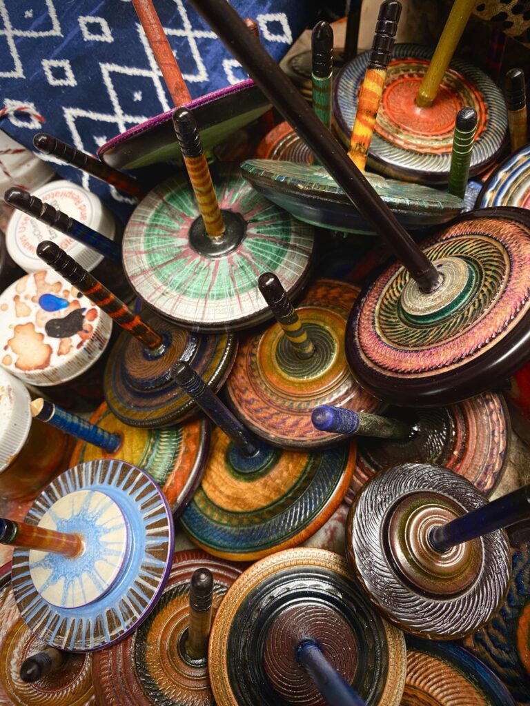 "THE ALL-NEW SPIN TOPS ‘25”
Just painted and lacquered off the lathe, these will go with me DEC. 6 to the Mighty Tieton Christmas Bazaar. Each one comes with your choice of Carol Barany’s string tie bags! The colors on these are really nice Betty Ann Cohen metallic jumbo Pen acrylics that really shimmer in the spin.